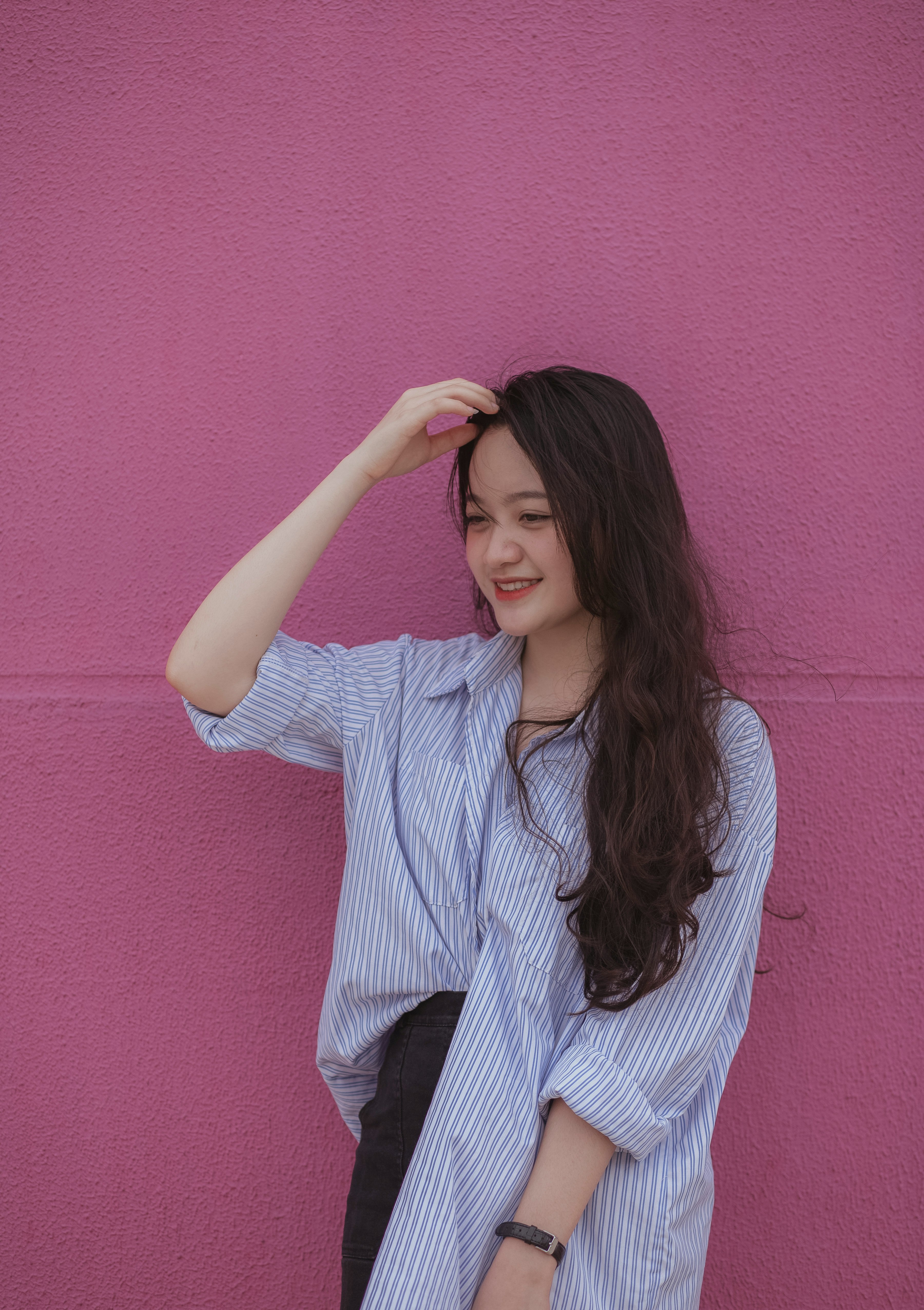 woman in blue and white striped dress shirt holding her hair