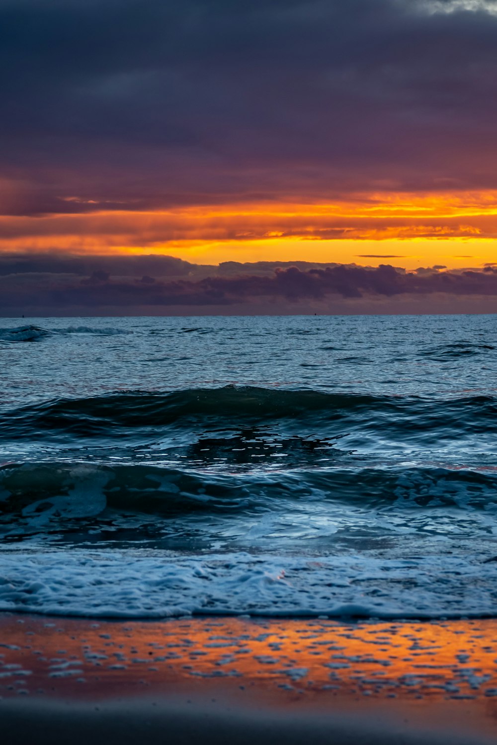 Onde dell'oceano sotto il cielo arancione durante il tramonto