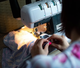 person sewing white sewing machine