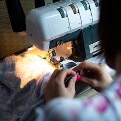 person sewing white sewing machine