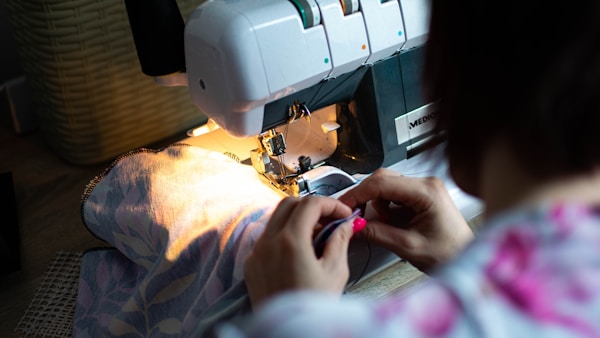 person sewing white sewing machine