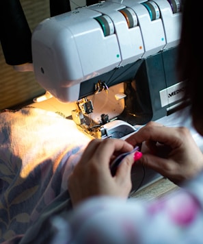 person sewing white sewing machine