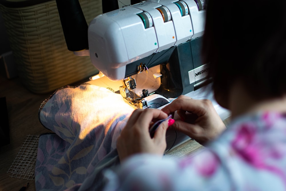 person sewing white sewing machine