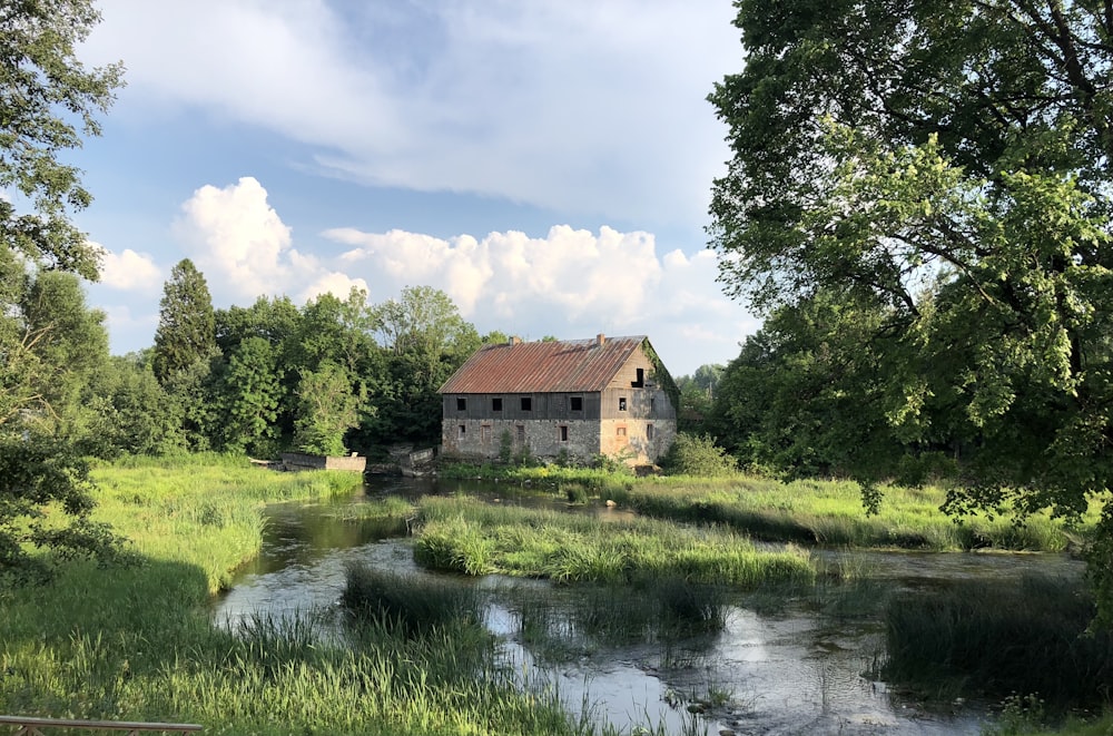 brown and white house near green trees and river under blue sky during daytime