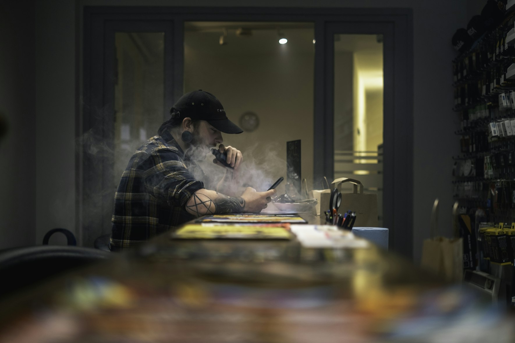 A guy sitting at a bar table vaping.