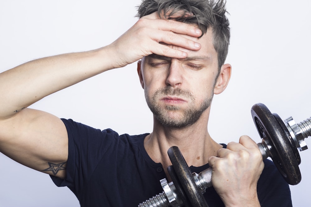 man in black crew neck t-shirt holding black dumbbell