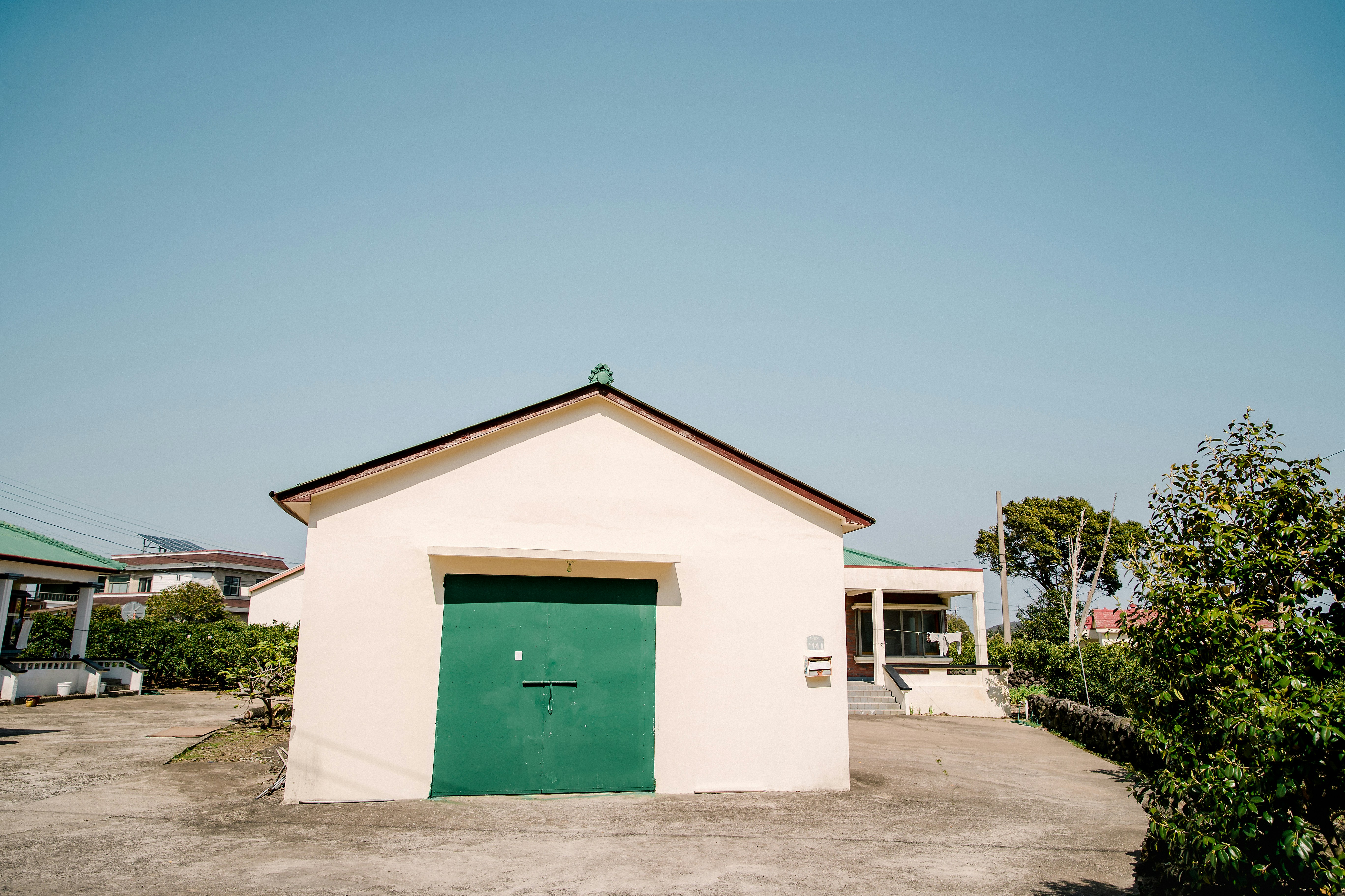 casa in cemento bianco e verde sotto il cielo blu durante il giorno