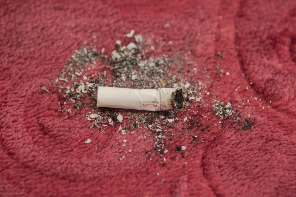 white cigarette stick on red textile