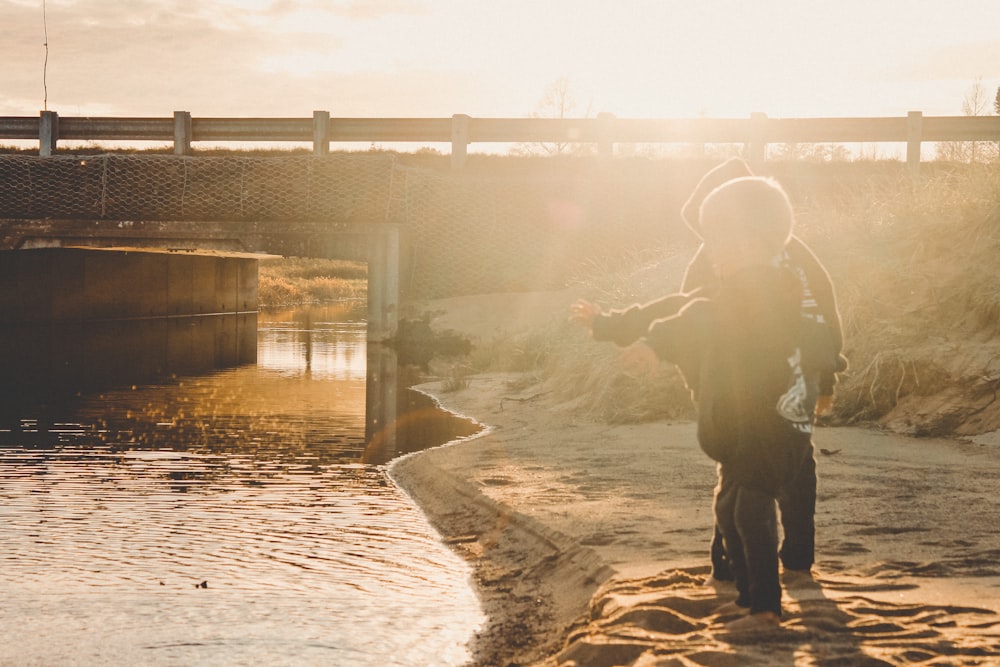 man in black jacket and pants standing beside body of water during daytime