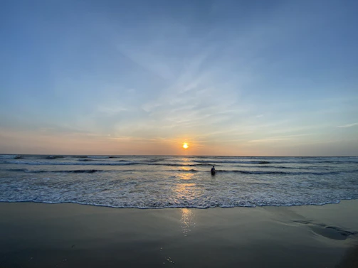 A calm Red Sea shoreline at sunset with gentle waves and a diving mask resting on the sand.