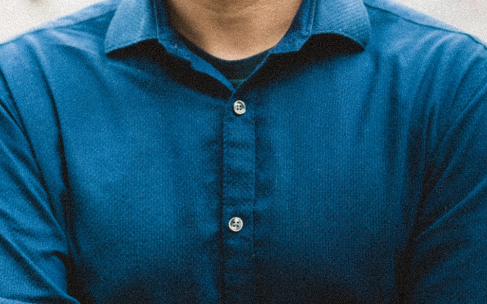 青いボタンアップシャツの男