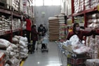A shopper happily loading bulk items into a cart in a warehouse-style store.