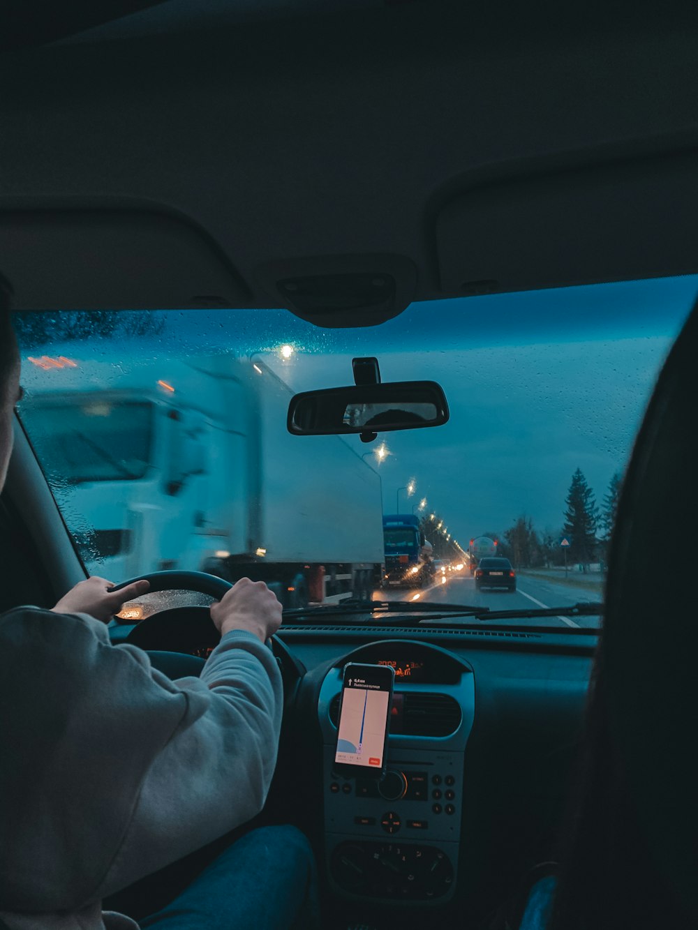 persona in camicia grigia a maniche lunghe che guida l'auto