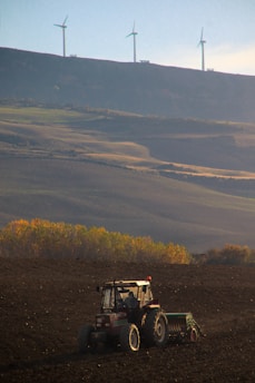 A tractor working the land at dawn with golden light.