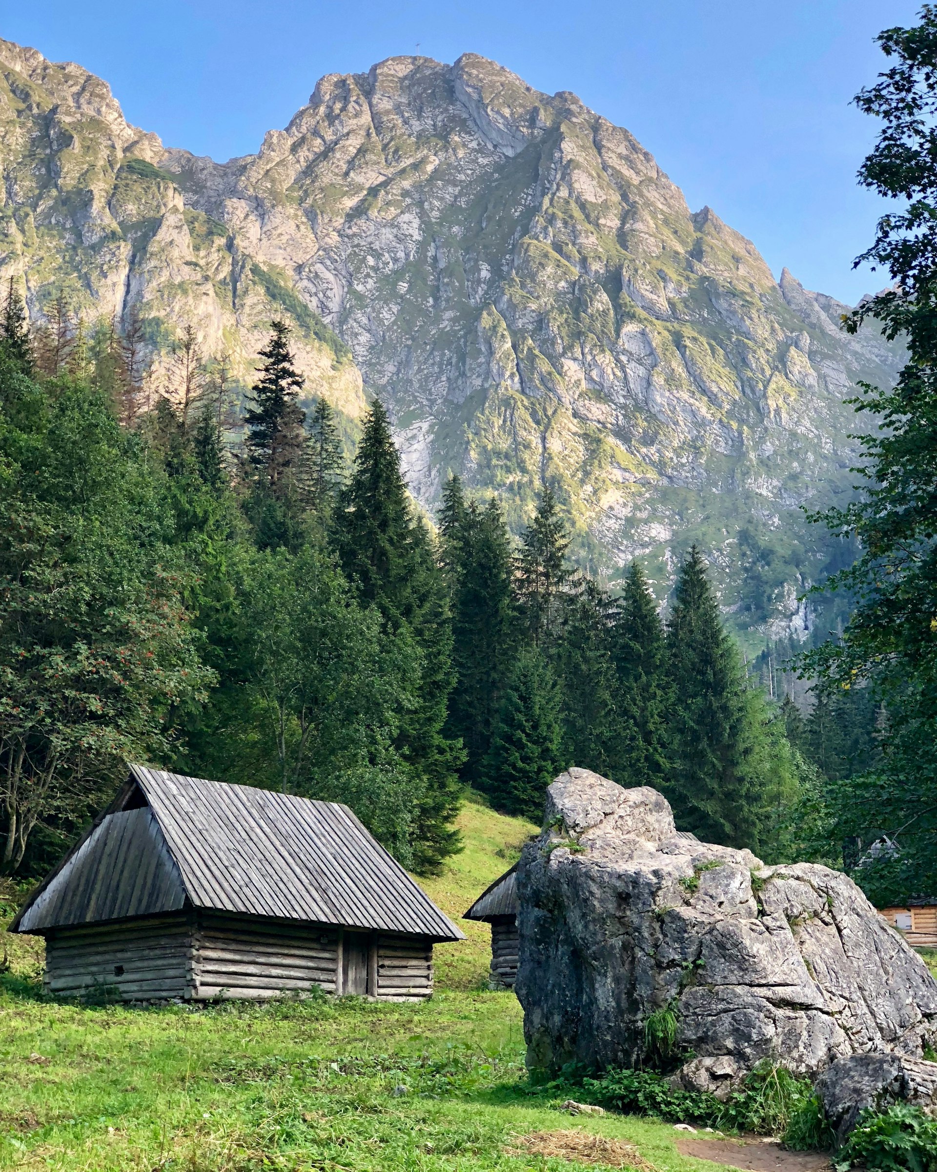 Traditional wooden hut in a mountain valley beneath the jagged Tatra peaks, Zakopane, Poland