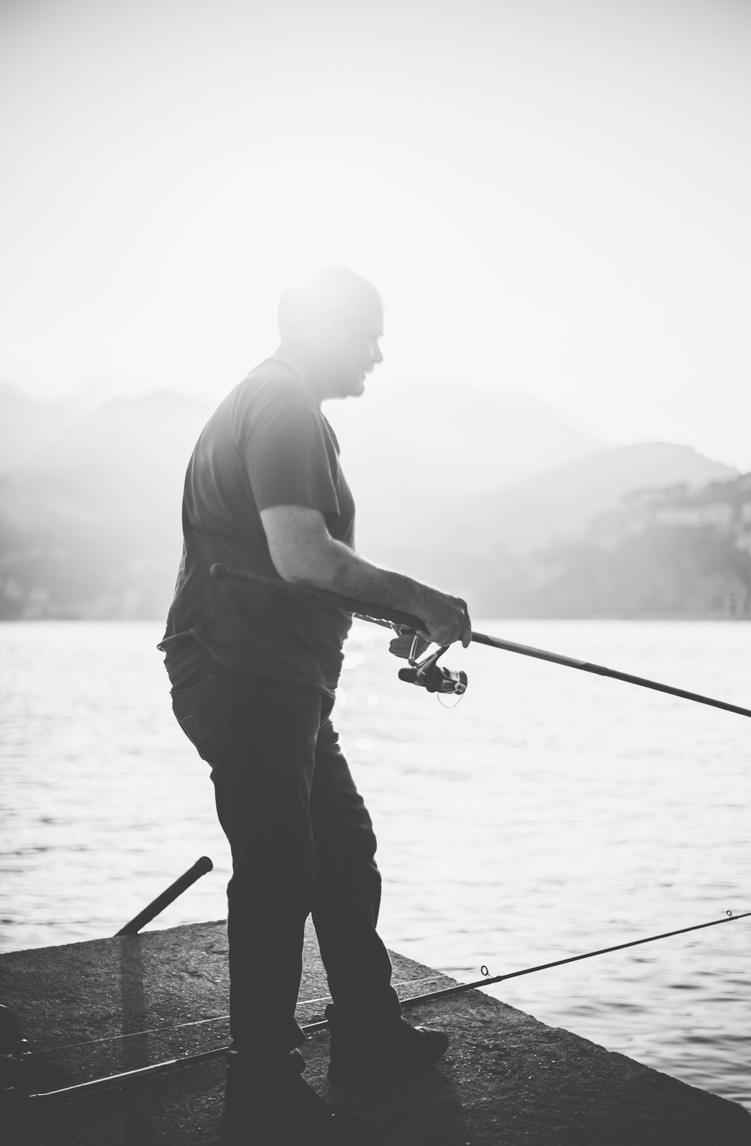 man in gray shirt and black pants fishing on lake during daytime