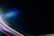A dark canvas is intersected by vibrant streaks of colored light, including reds, blues, greens, and purples, creating a dynamic and futuristic atmosphere. The light patterns appear to move across the image, giving a sense of motion.