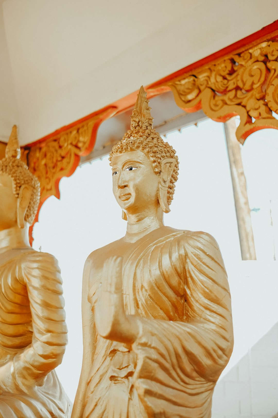 gold buddha statue near orange curtain