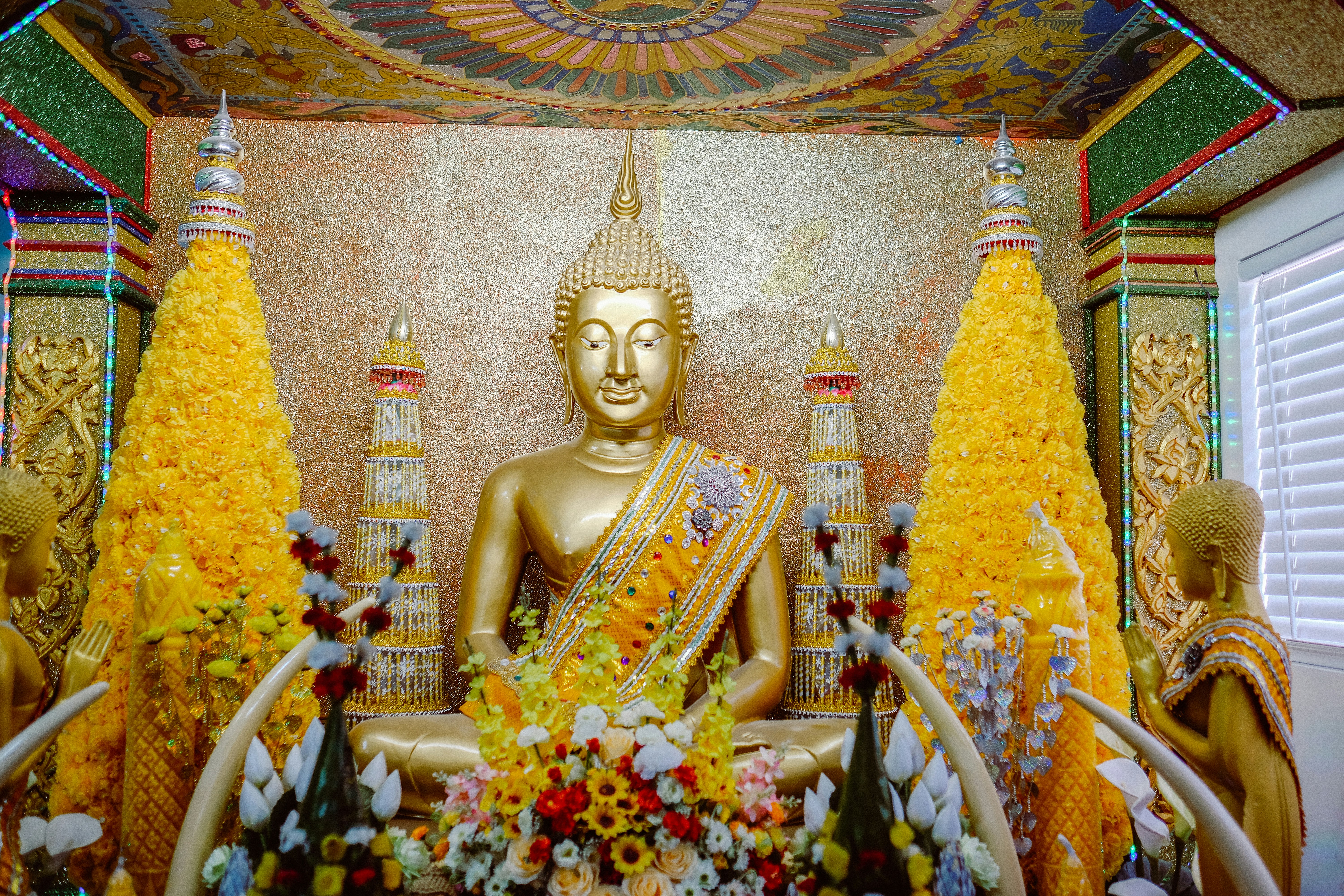 gold buddha statue surrounded by flowers