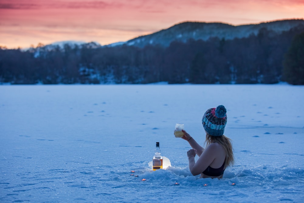 woman in black bikini top holding clear plastic bottle on water