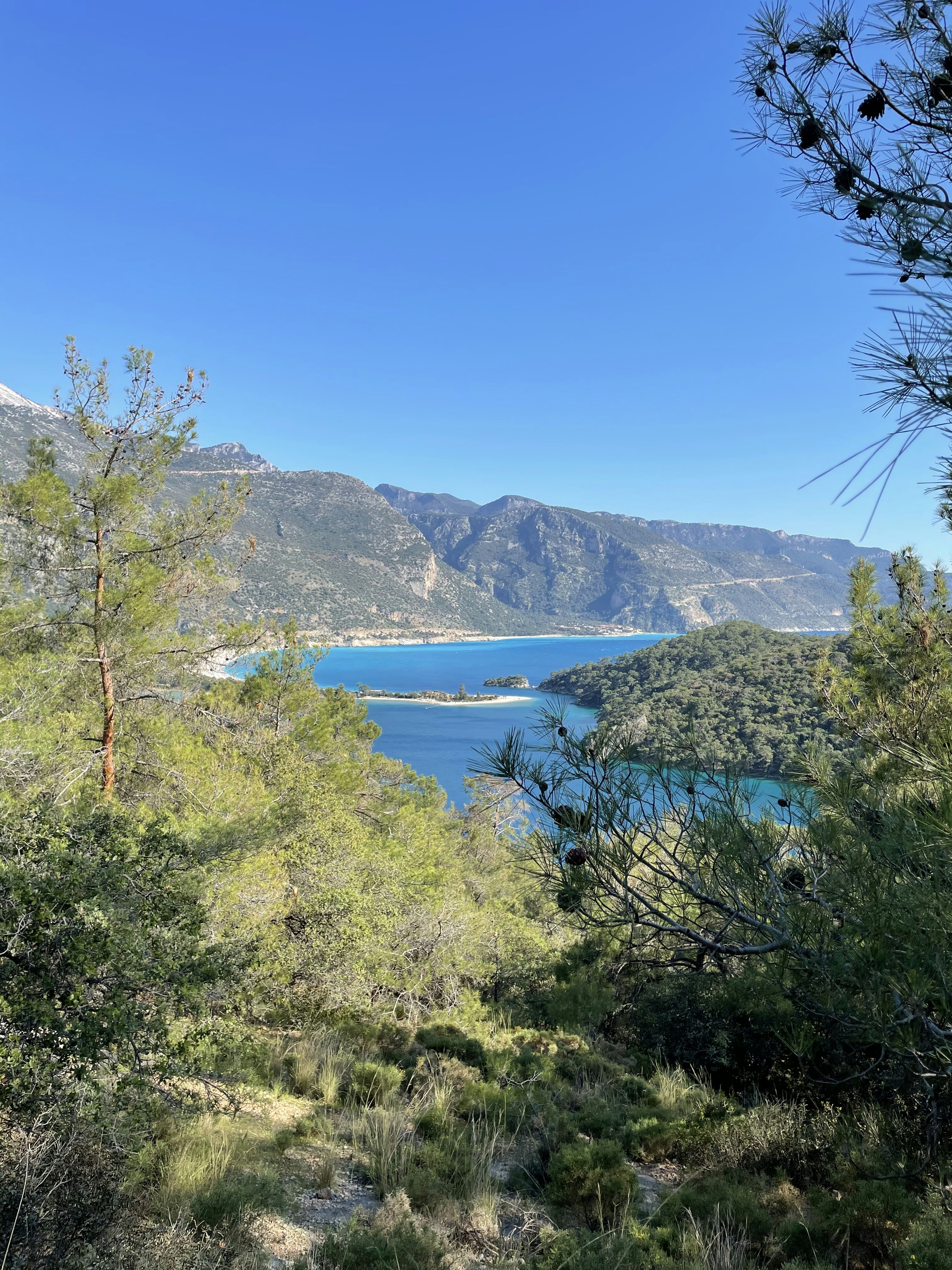 Fethiye bay at golden hour, turquoise water, pine-covered hills, natural Mediterranean landscape