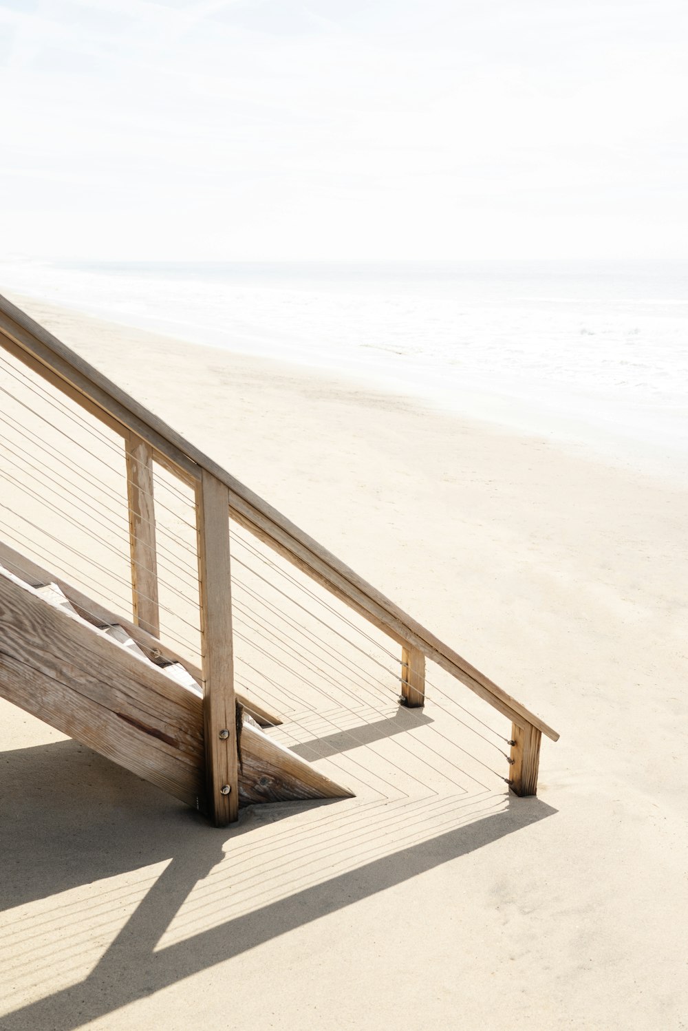 Escalera de madera marrón en la playa de arena blanca durante el día