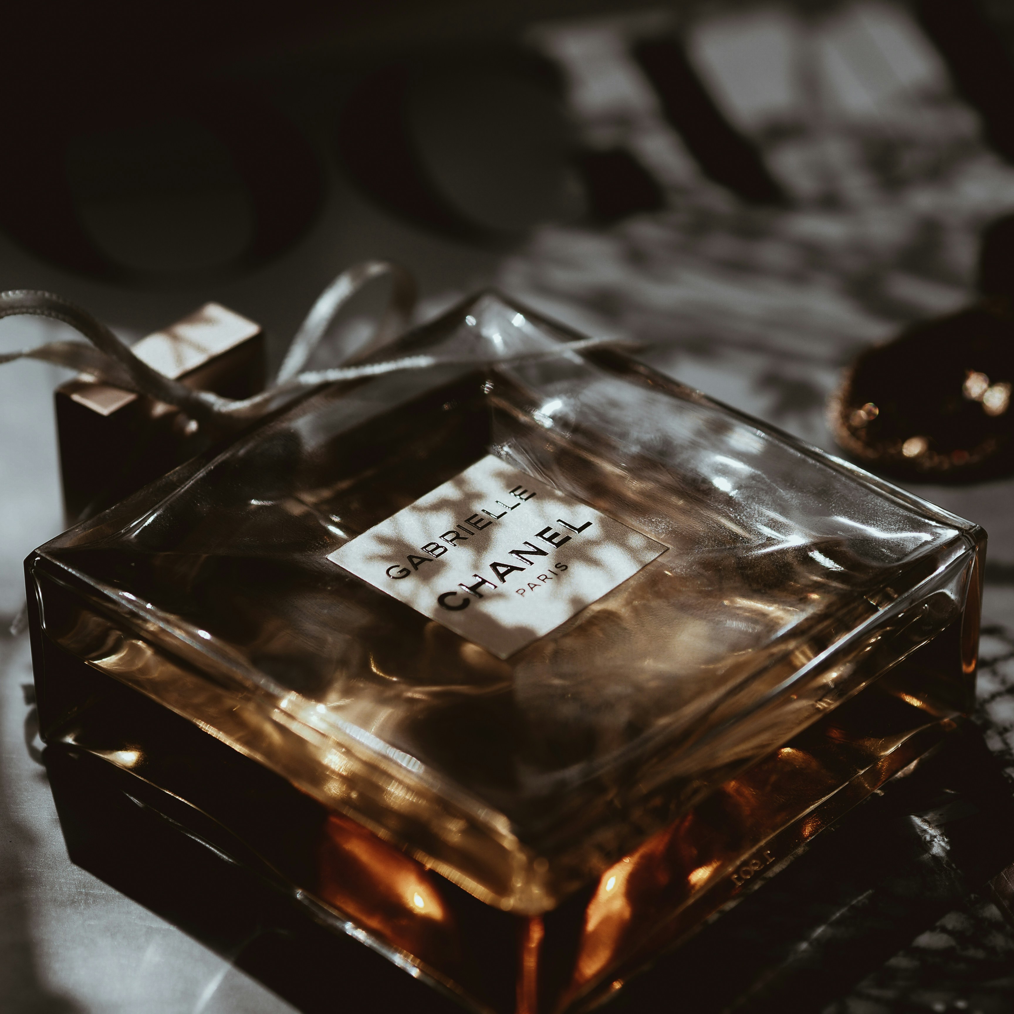 Chanel perfume bottle in elegant white and gold packaging on a marble surface with soft warm light