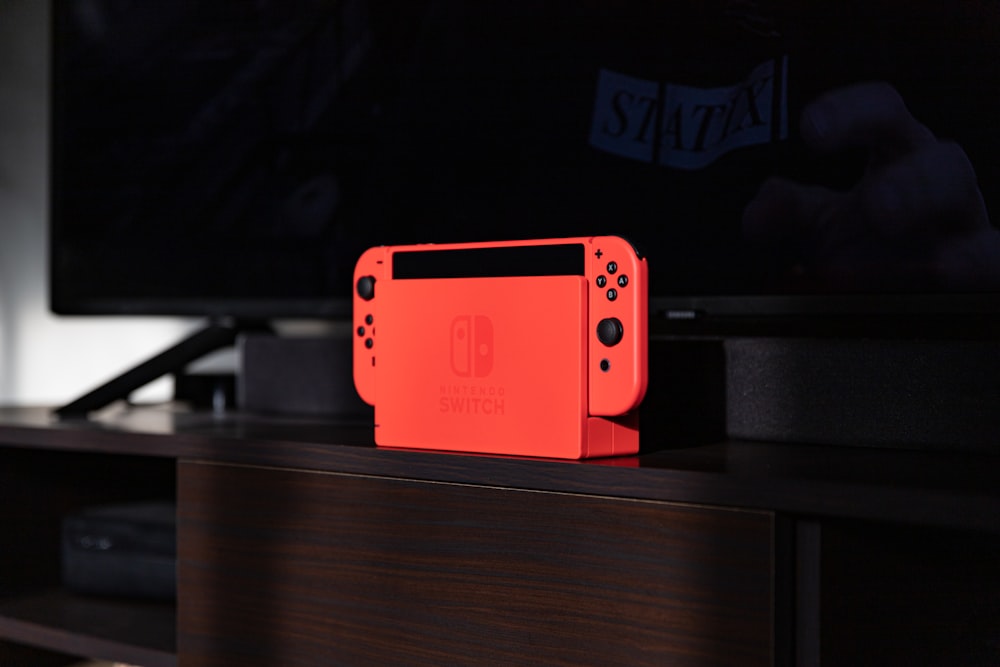 red nintendo switch on brown wooden table