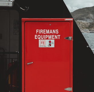 a red fireman's equipment box sitting on the side of a building