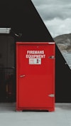 a red fireman's equipment box sitting on the side of a building