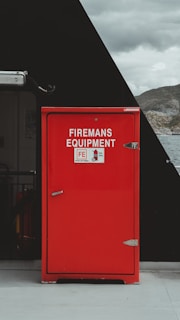 a red fireman's equipment box sitting on the side of a building