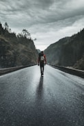 person in black jacket and black pants walking on road during daytime