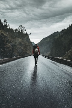 person in black jacket and black pants walking on road during daytime