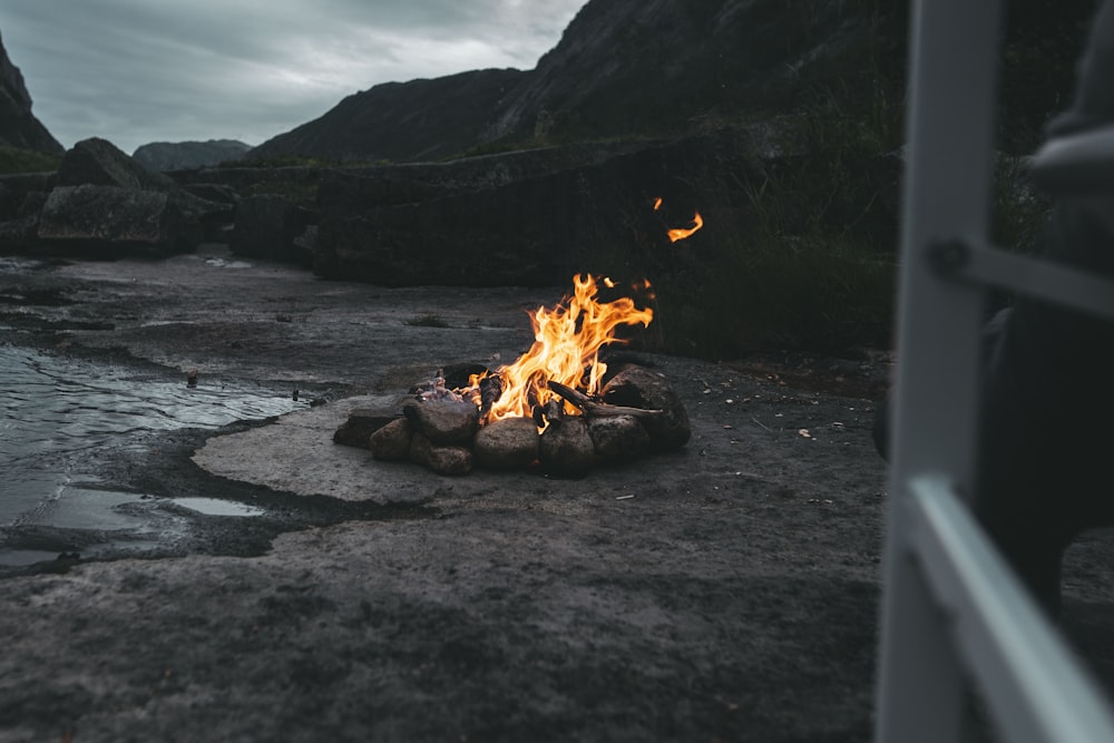 fire on black sand near body of water during daytime