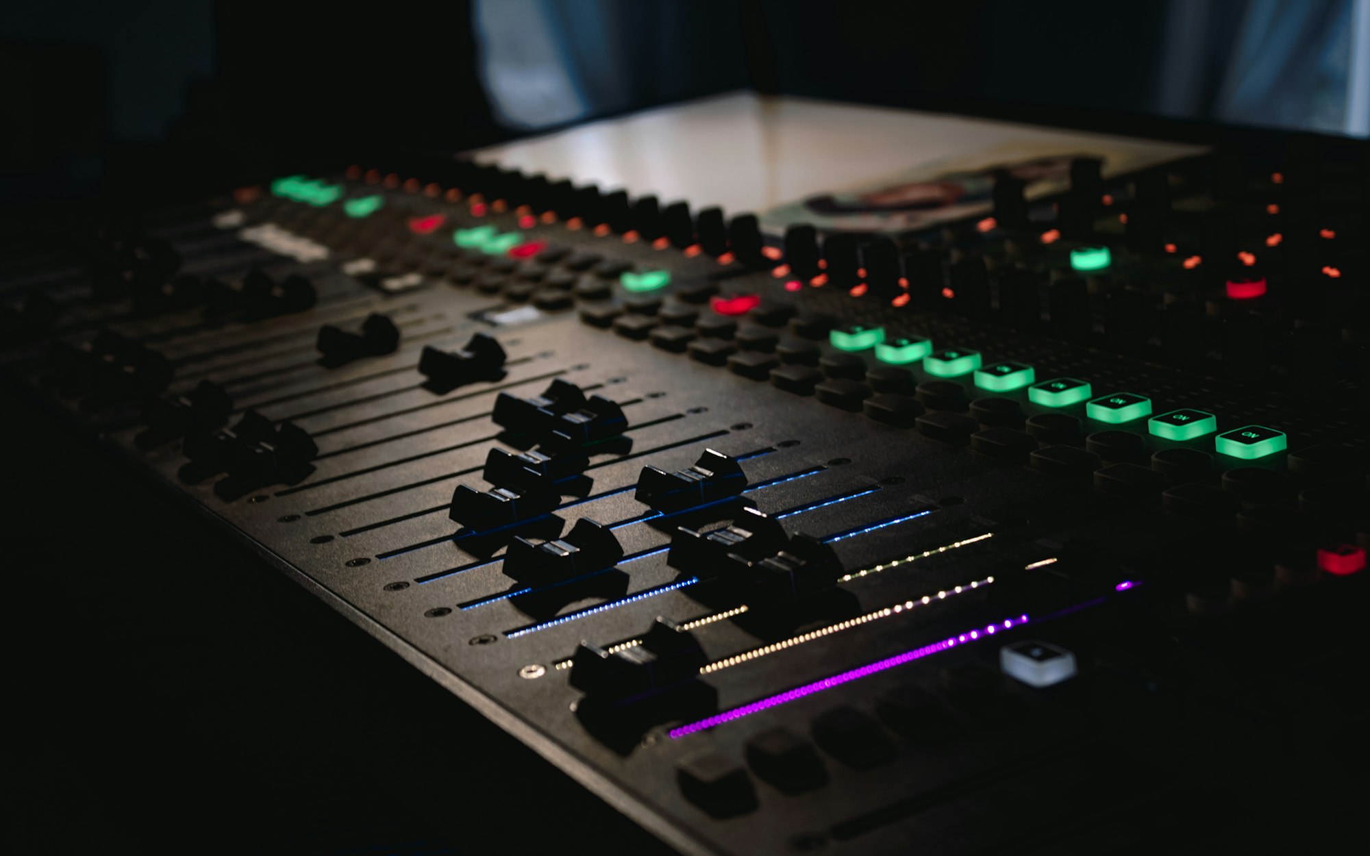 Dj's Mixing console with bright buttons make sounds on dark background. Sound engineer inside party