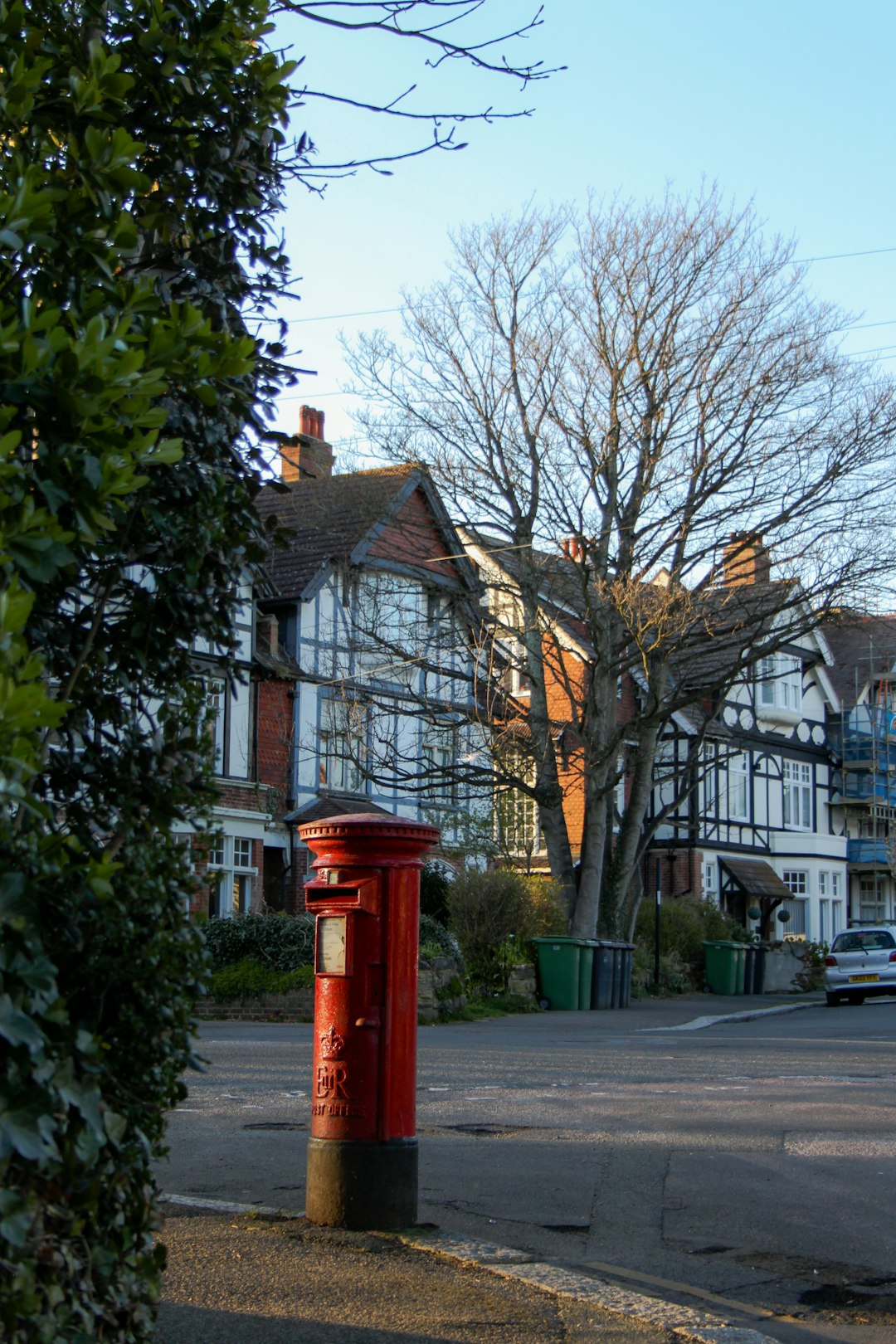 red telephone booth near bare tree during daytime