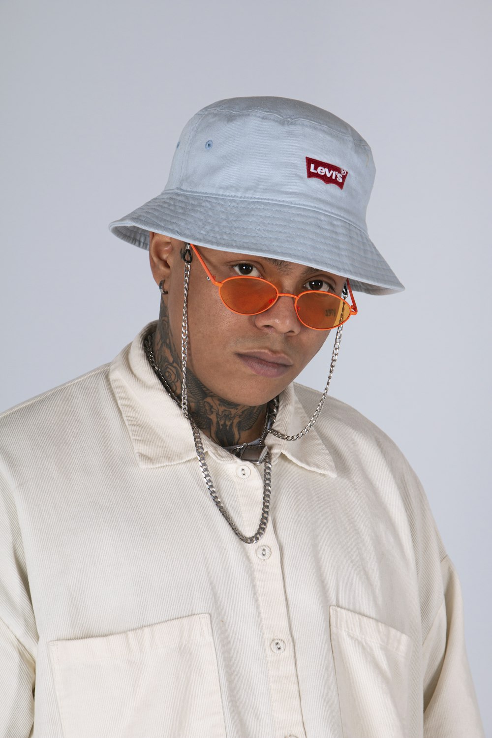 man in white crew neck shirt wearing gold framed aviator sunglasses and white fitted cap