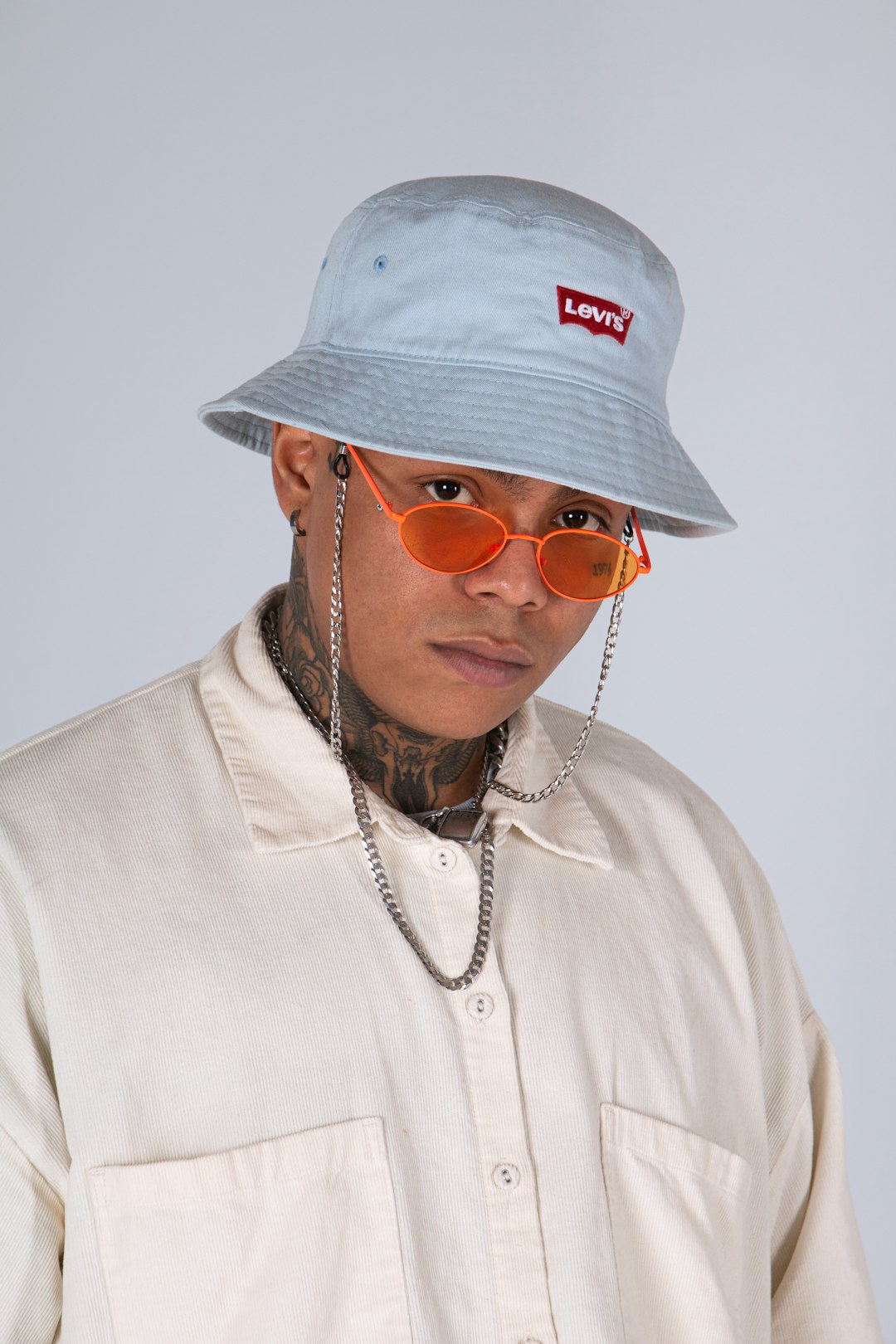 man in white crew neck shirt wearing gold framed aviator sunglasses and white fitted cap