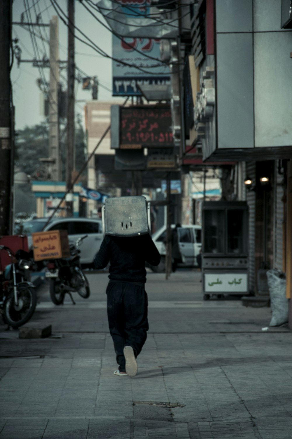 man in black jacket and black pants walking on sidewalk during daytime