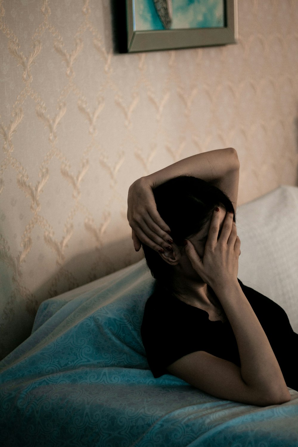 woman in black shirt covering face with blue blanket