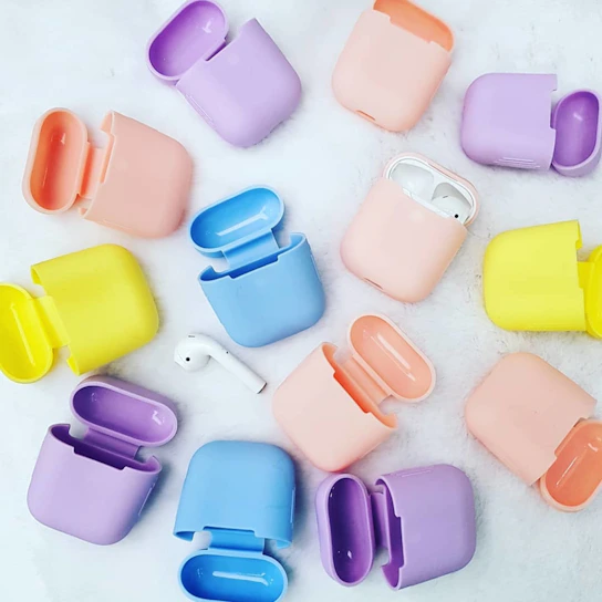 A vibrant display of wireless earbuds and phone cases in various colors on a clean white background.