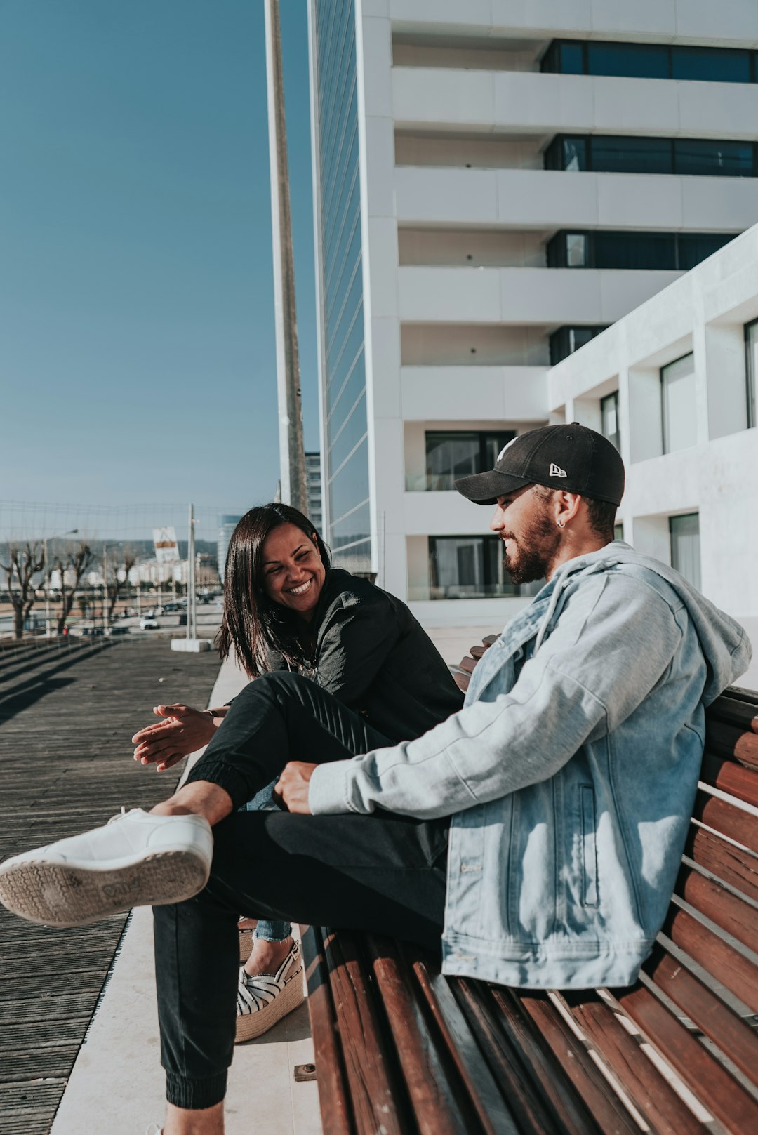 man and woman sitting on brown wooden bench during daytime