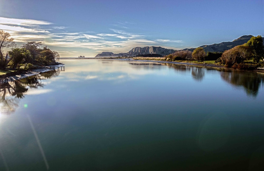 body of water near mountain under blue sky during daytime