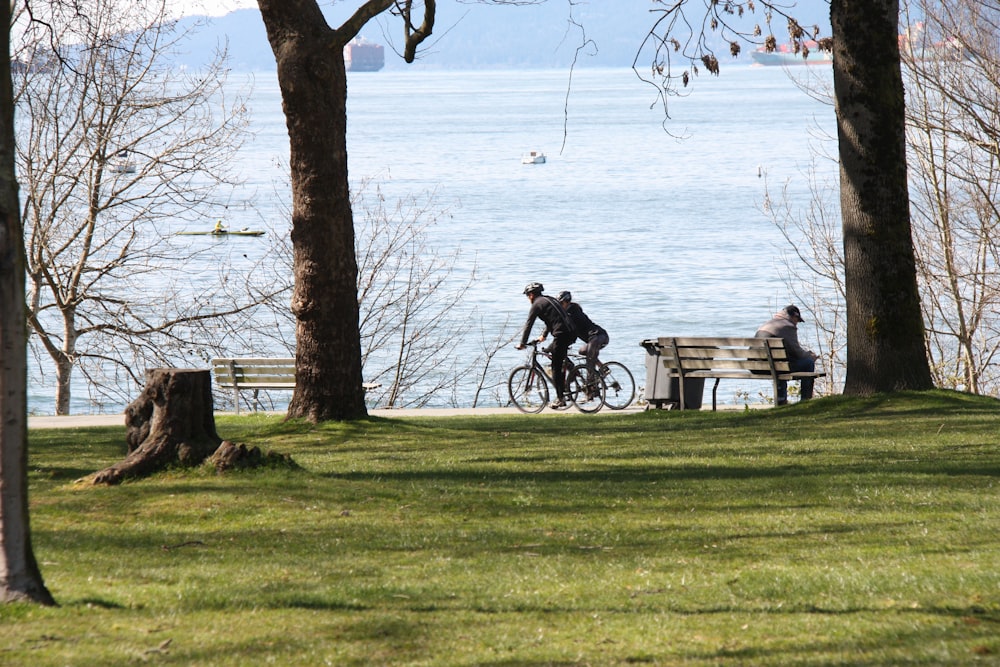 man in black jacket sitting on bench near body of water during daytime