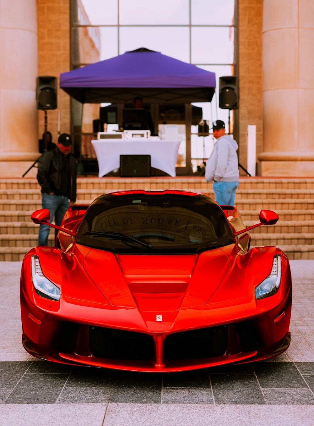 auto sportiva rossa ferrari davanti alla gente che cammina sulla strada durante il giorno