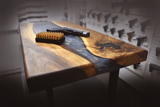 A sleek black Glock pistol displayed on a wooden table with natural light highlighting its details.