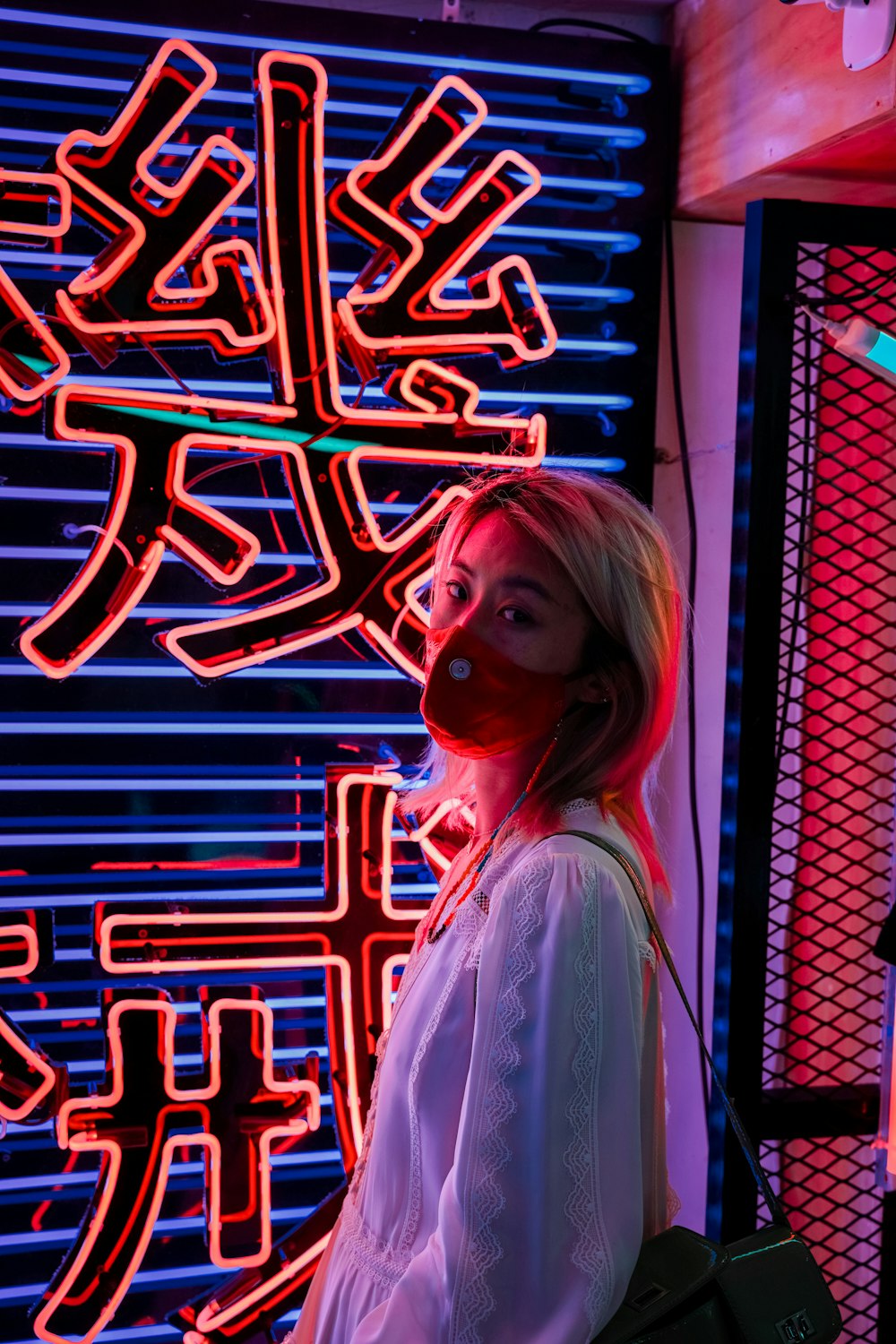woman in white shirt standing near red and blue neon light signage