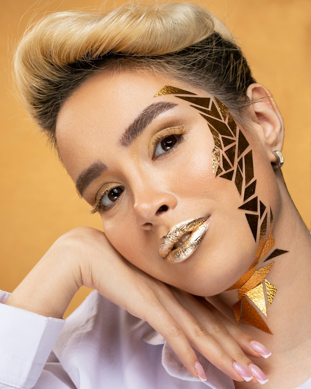 woman in white and orange top with gold heart shaped earrings