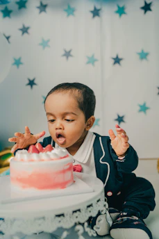 boy in black and white jacket holding pink cake