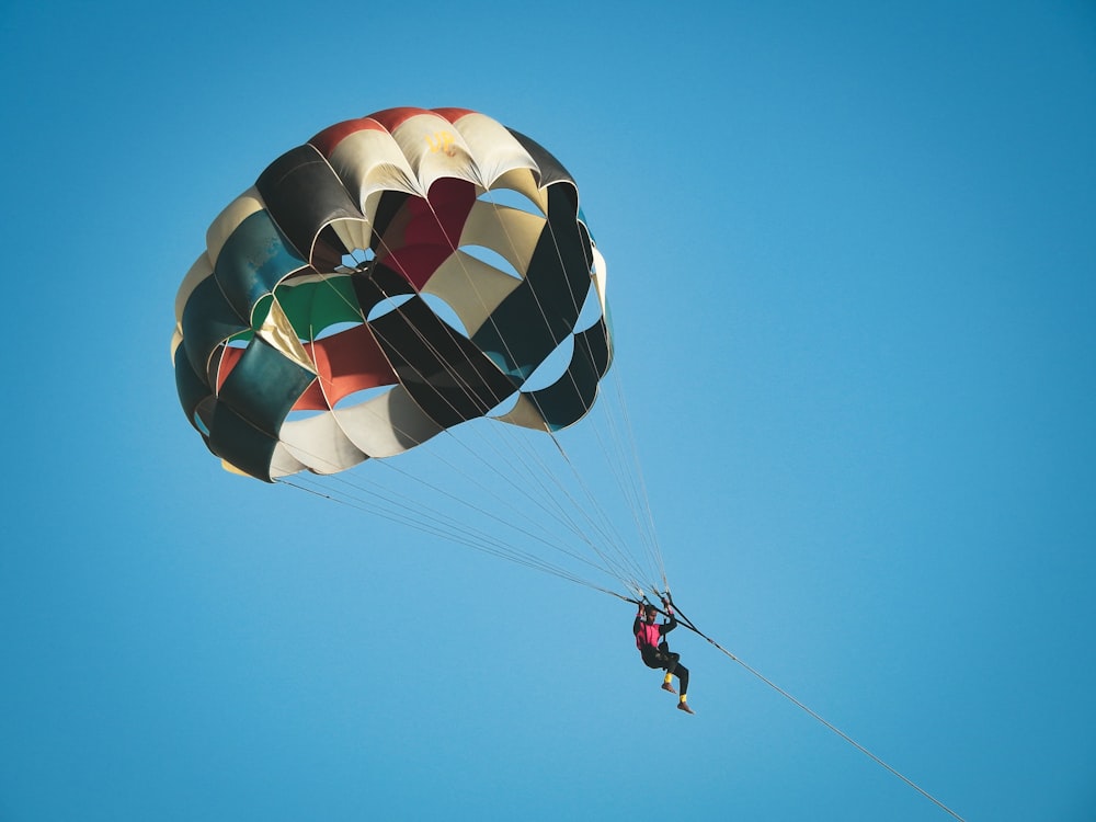 person in red jacket riding on yellow blue and red parachute